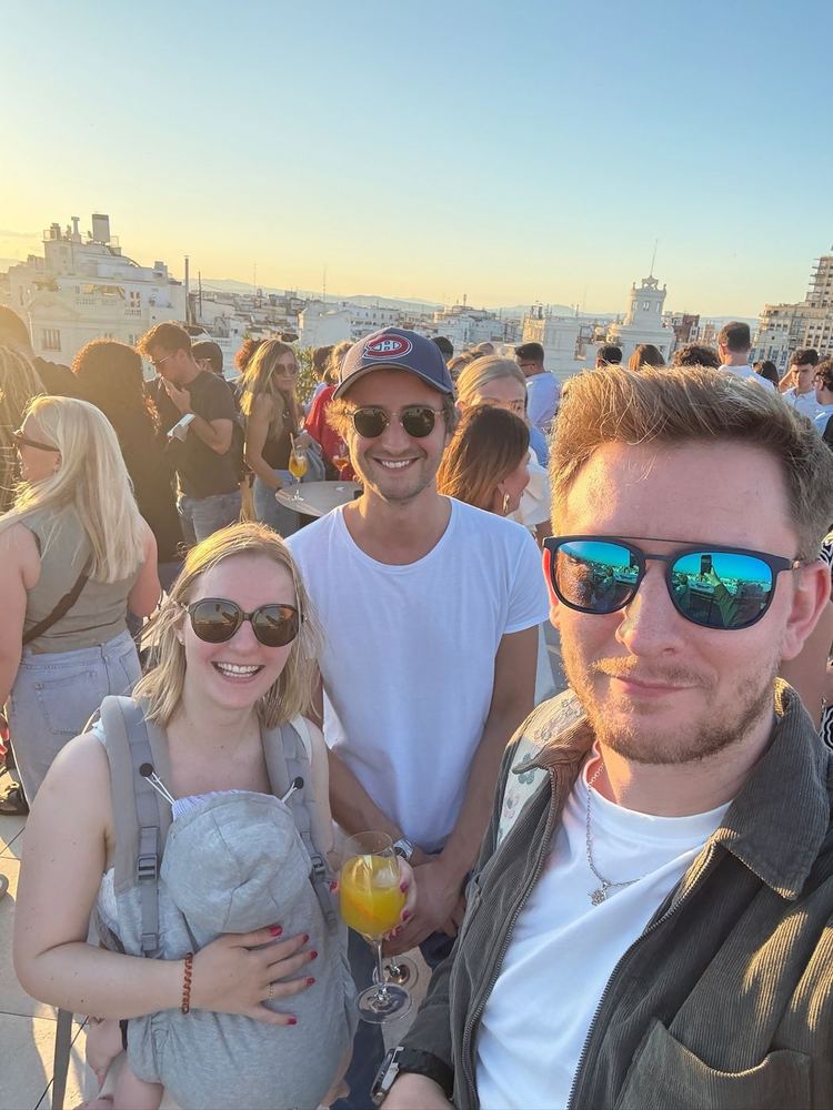 Charles, sa compagne et leur fille sur un toit-terrasse, au coucher du soleil.