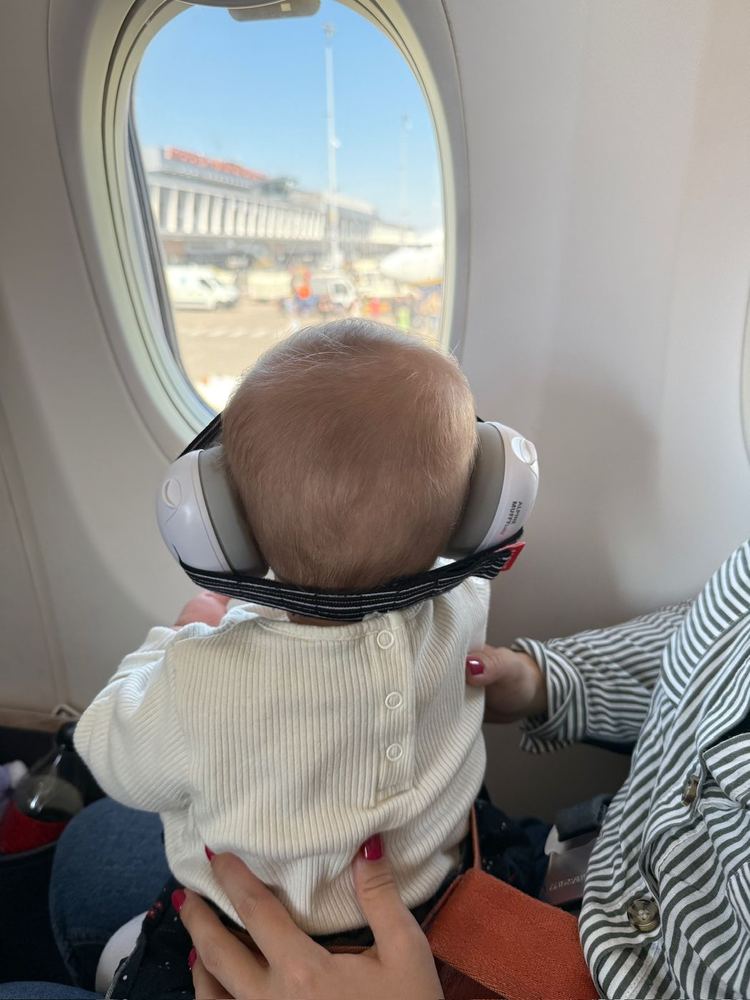 Sa fille regarde par le hublot d’un avion, casque anti-bruit sur les oreilles.